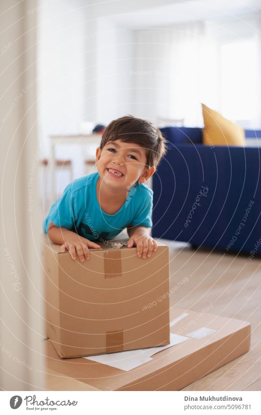 4 oder 5 Jahre alter Junge, der mit Kartons spielt, nachdem er mit seiner Familie in eine neue Wohnung gezogen ist. Freude über den Umzug in eine neue Wohnung. Lächelndes Kind, das einen Karton hält.