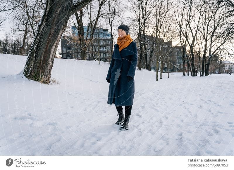 Eine Frau geht auf dem schneebedeckten Boden und lächelt Lächeln Winter kalt Schnee Fröhlichkeit Glück Freude Menschen Person Erwachsener Mantel heiter allein