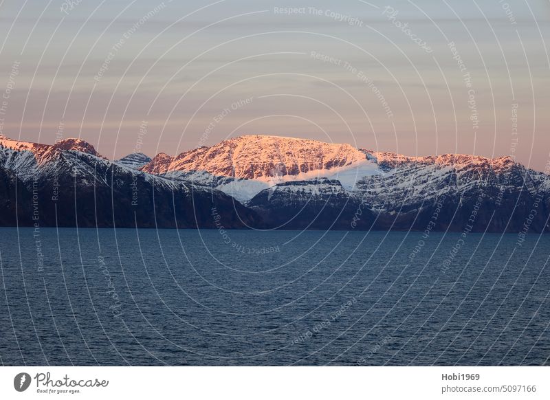 Sonnenaufgang an der Küste bei Alta in Norwegen. Die Berge werden von der Sonne angestrahlt. alta norwegen küste sonnenaufgang berg berge fjord schnee