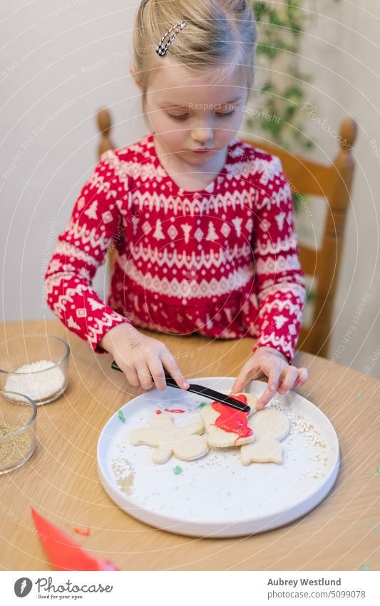 kleines Mädchen beim Verzieren von frisch gebackenen Weihnachtsplätzchen Schönheit Feier Kind Kindheit Kinder Weihnachten Weihnachtsbaum Nahaufnahme Keks