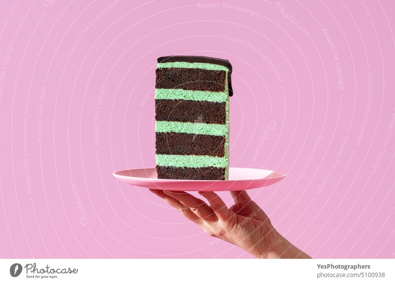 Geschichtete Kuchenscheibe auf einem Teller, minimalistisch auf einem lila Hintergrund. Transparente Geburtstag schwarz hell Buttercreme Feier Schokolade