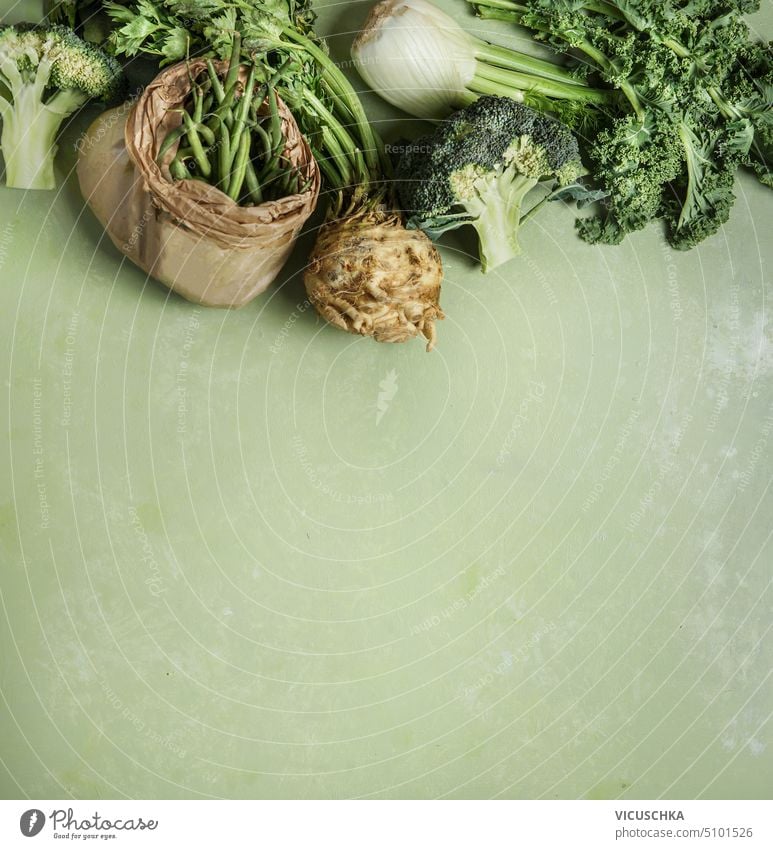 Verschiedene grüne Gemüse: Grünkohl, Brokkoli, Fenchel, grüne Bohnen, Sellerie auf grünem Hintergrund, Ansicht von oben. Gesundes Essen verschiedene Kale