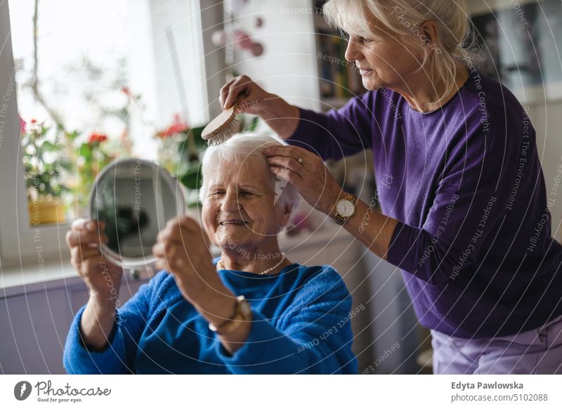 Frau kämmt die Haare ihrer älteren Mutter Lächeln Glück genießend positiv Freude Menschen Senior reif heimwärts Haus alt Alterung häusliches Leben Großmutter