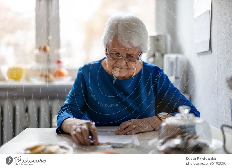 Ältere Frau beim Ausfüllen des Jahresabschlusses Lächeln Glück genießend positiv Freude Menschen Senior reif älter heimwärts Haus alt Alterung häusliches Leben