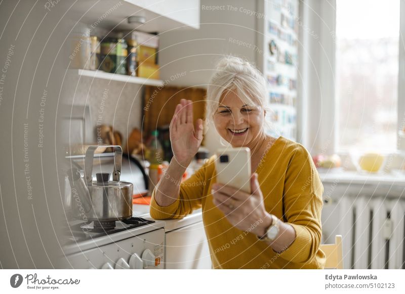 Ältere Frau benutzt Mobiltelefon zu Hause Lächeln Glück genießend positiv Freude Menschen Senior reif älter heimwärts alt Alterung häusliches Leben Großmutter