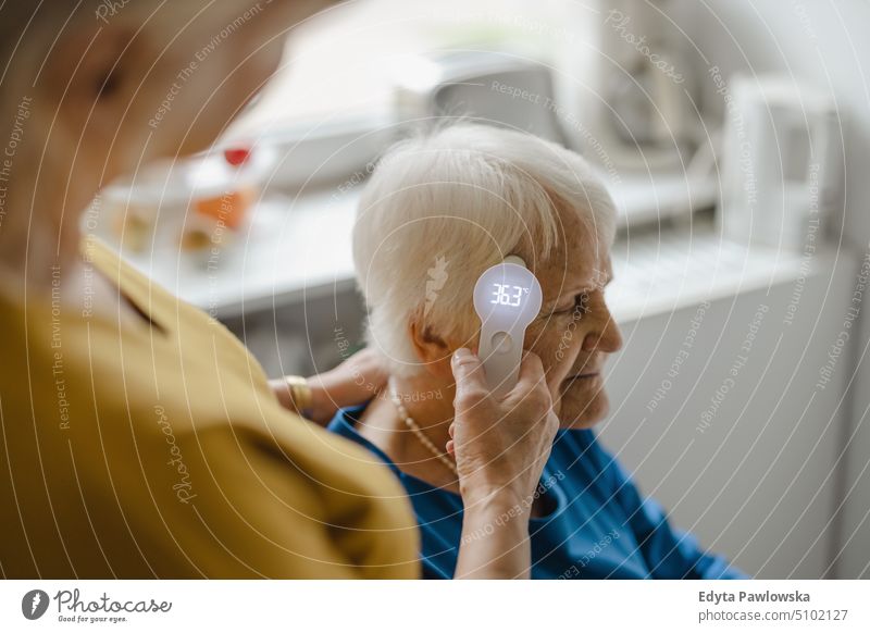 Pflegekraft prüft Temperatur einer älteren Frau Lächeln Glück genießend positiv Freude Menschen Senior reif heimwärts Haus alt Alterung häusliches Leben