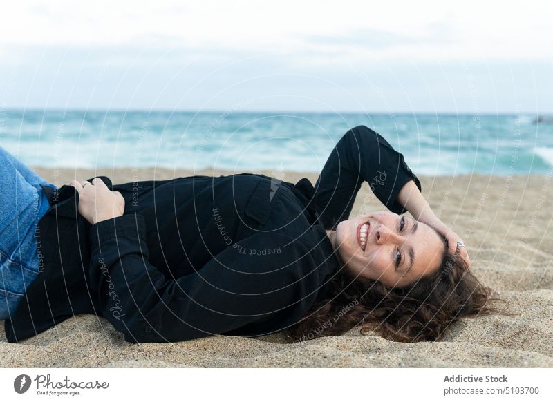 Fröhliche Frau auf Sand liegend Strand Lügen Freude Küste Freizeit Kälte Spaß haben heiter Lächeln MEER Glück positiv jung sich[Akk] entspannen ruhen