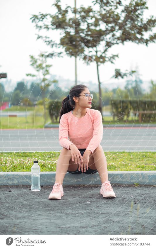 Sportlerin mit Wasserflasche auf Bordsteinkante sitzend Pause ruhen Seitenstreifen Läufer Freizeit Gesundheit physisch Wohlbefinden passen Frau Athlet