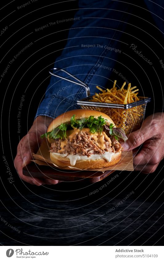 Crop Person mit leckerem Burger Hand Fastfood Junk Food Pommes frites kulinarisch Mahlzeit Lebensmittel ungesund Kalorie Salat Schweinefleisch Brötchen Fleisch