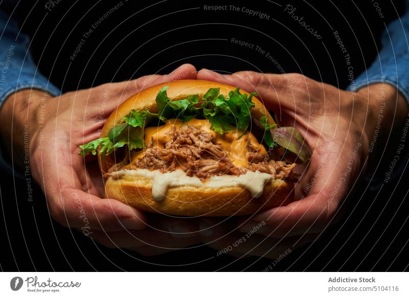 Crop Person mit leckerem Burger Hand Fastfood Junk Food kulinarisch Mahlzeit Lebensmittel ungesund Kalorie Salat Schweinefleisch Brötchen Fleisch Geschmack