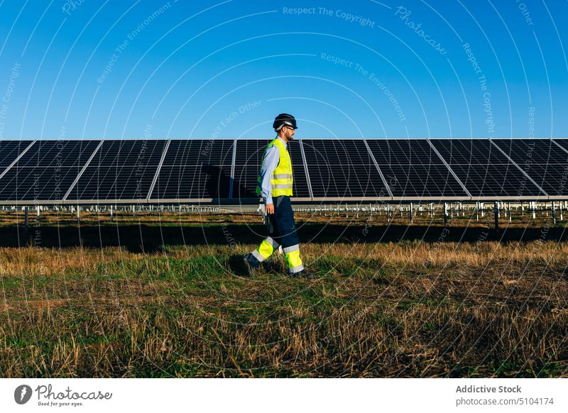 Techniker im Vorbeigehen an Photovoltaikzellen im Feld Mann Sonnenkollektor nachhaltig alternativ umweltfreundlich Energie Erneuerung männlich professionell Öko