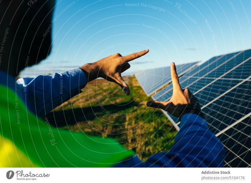 Crop-Mitarbeiter zeigt Rahmengeste gegen Sonnenkollektoren Techniker Arbeiter Photovoltaik Batterie Erneuerung nachhaltig alternativ Rahmengebärde Fotogeste