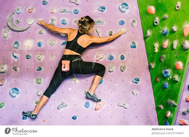 Weiblicher Kletterer an der Wand hängend Sportlerin Training Aufstieg Fitnessstudio Griff üben Frau Kraft Bouldern extrem Aktivität anstrengen Aufsteiger