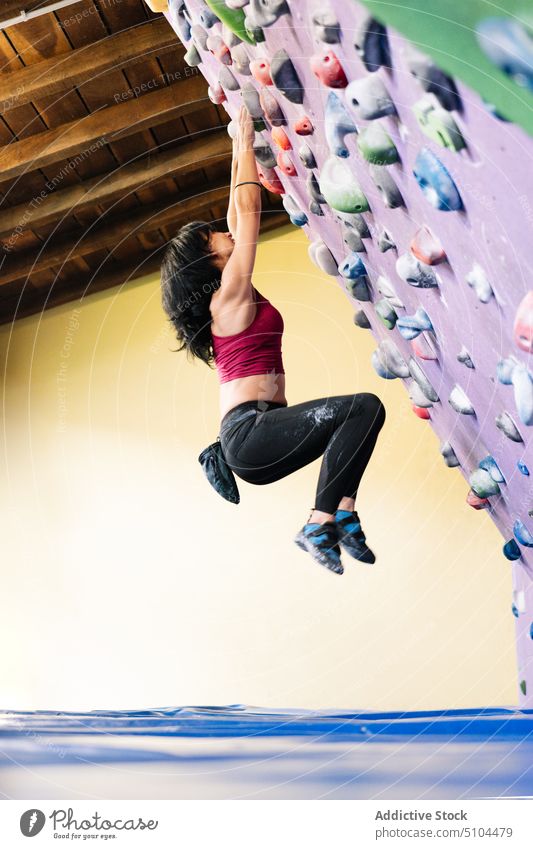 Weibliche Kletterin hängt an schräger Wand Sportlerin hängen Training Aufstieg Neigung Fitnessstudio Griff üben Frau Unterlage Kraft Bouldern extrem Aktivität