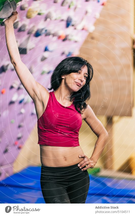 Kletterin macht Pause in der Nähe der Wand Sportlerin Aufsteiger fettarm selbstbewusst Fitnessstudio Training Lächeln Frau Hand auf der Taille Aufstieg stark