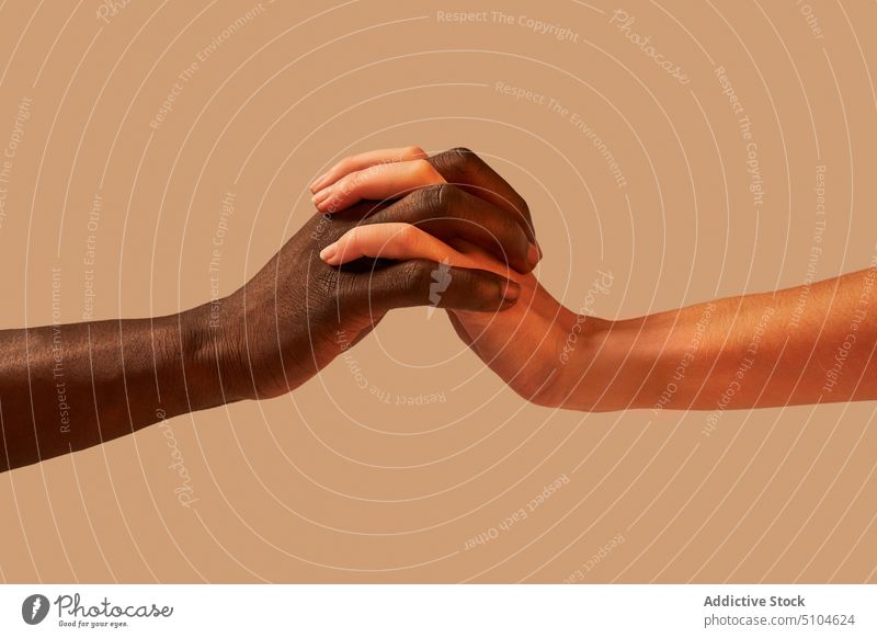 Unerkennbares gemischtrassiges Paar hält sich an den Händen Händchenhalten Zusammensein Angebot Toleranz Einheit Kontrast Partnerschaft Atelier Bonden