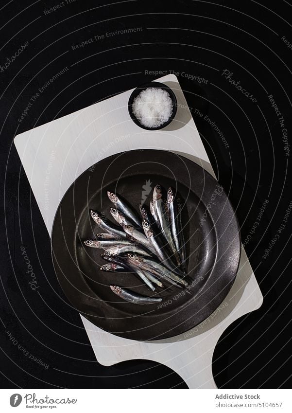 Rohe kleine Fische in einem Teller auf dunklem Hintergrund Asiatische Küche Sardinen Omega drei Mahlzeit Italienisch geschmackvoll Meeresfrüchte Anchovis