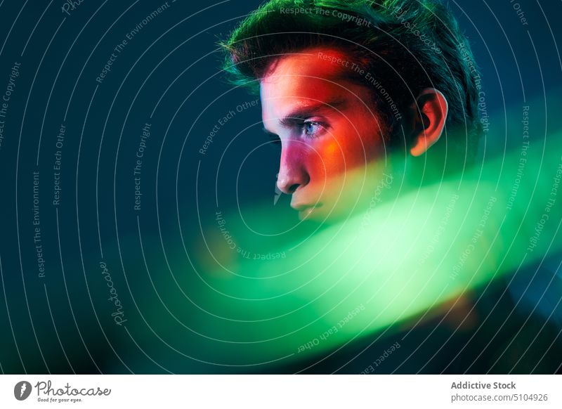 Profil eines jungen Mannes in Neonbeleuchtung Model Porträt mehrfarbig neonfarbig Licht Studioaufnahme Individualität emotionslos männlich leuchtend Blitze hell
