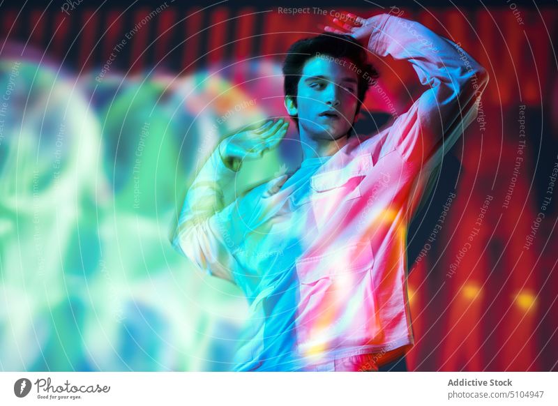 Moderner Mann im Neonlicht stehend Model Studioaufnahme Augen geschlossen neonfarbig mehrfarbig leuchten Individualität Projektor emotionslos Kunst männlich