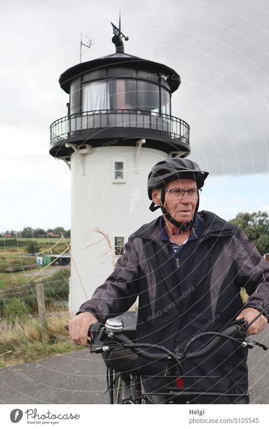 naturverbunden | Senior steht mit dem Fahrrad vor der "Dicken Berta" auf dem Elberadweg in Cuxhaven Mensch Mann Radfahrer Radtour radeln Dicke Berta Leuchtturm
