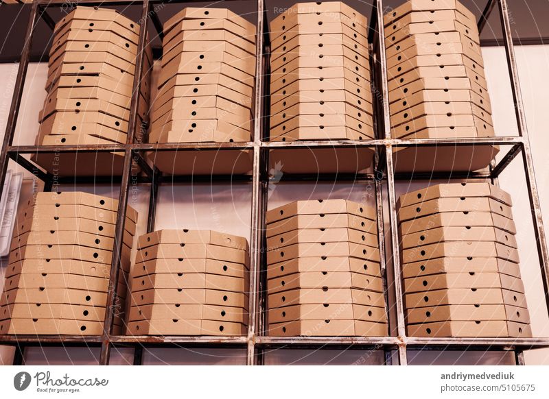 lebensmittel-lieferdienst. hohe stapel flacher brauner pizzakartons auf metallregal bereit für die lieferung. handwerkliche verpackungskartons mit pizza auf lager