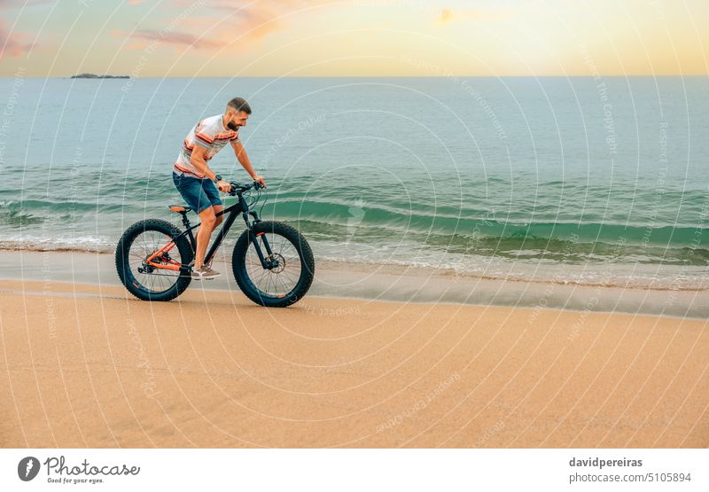 Junger Mann fährt auf einem Fatbike am Strand jung Reiten Meeresufer Textfreiraum Lächeln genießen Spaß Sand MEER Person Landschaft Spielen Sport Fahrrad