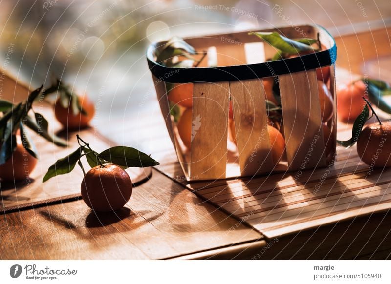 Ein Korb mit Mandarinen Obst Spankorb Früchte Blätter Licht Lebensmittel Gesundheit Frucht Gesunde Ernährung Bioprodukte Vitamin fruchtig vitaminreich Tisch