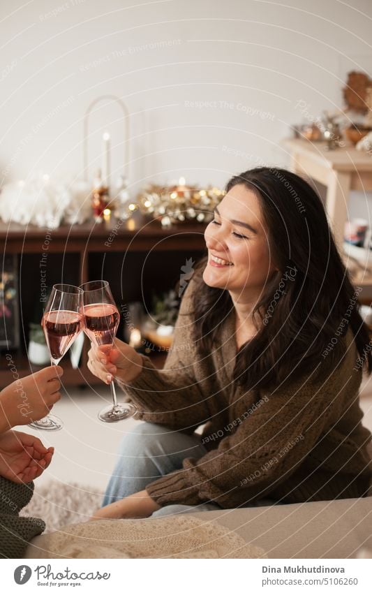Junge erwachsene kaukasische Frau jubelt mit Sekt mit ihrem Freund oder Partner, lächelnd und lachend. Frauen feiern Urlaub und trinken. St Valentines's Day oder Weihnachten Urlaub Saison Feier zu Hause Wohnung.