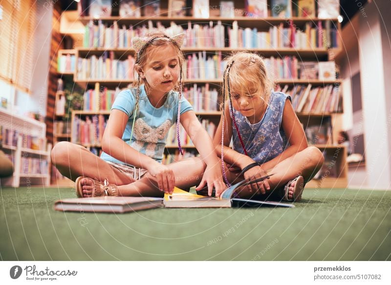 Zwei Schülerinnen lesen Bücher in der Schulbibliothek. Grundschüler, die aus Büchern lernen. Schüler machen Hausaufgaben. Kinder haben Spaß im Schulclub. Zurück zur Schule