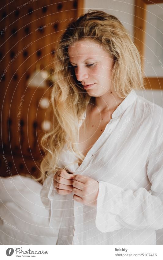 blonde junge Frau beim Anziehen eines weißen Hemdes umziehen ausziehen Model schön attraktiv Fahsion natürlich zuknöpfen aufknöpfen Garderobe Kleidung ankleiden