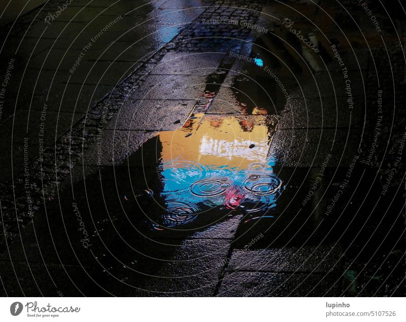 Leuchtreklame spiegelt sich in Pfütze Regen nachts Stadt November orange blau Schatten Ausschnitt Wasserkreise Menschen Spiegelungen