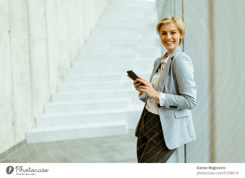 Geschäftsfrau benutzt Mobiltelefon in einem modernen Büroflur Erwachsener attraktiv Schönheit brünett Business Geschäftsperson Geschäftsleute Geschäftsmann