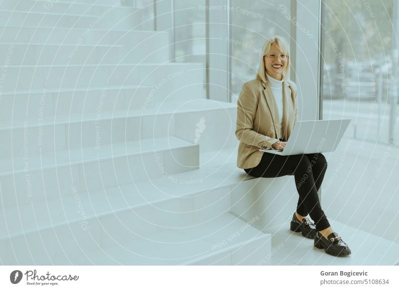 Geschäftsfrau mit Laptop auf moderner Bürotreppe Erwachsener Brille blond Business Geschäftsperson Geschäftsleute Geschäftsmann Kaukasier Mitteilung Computer