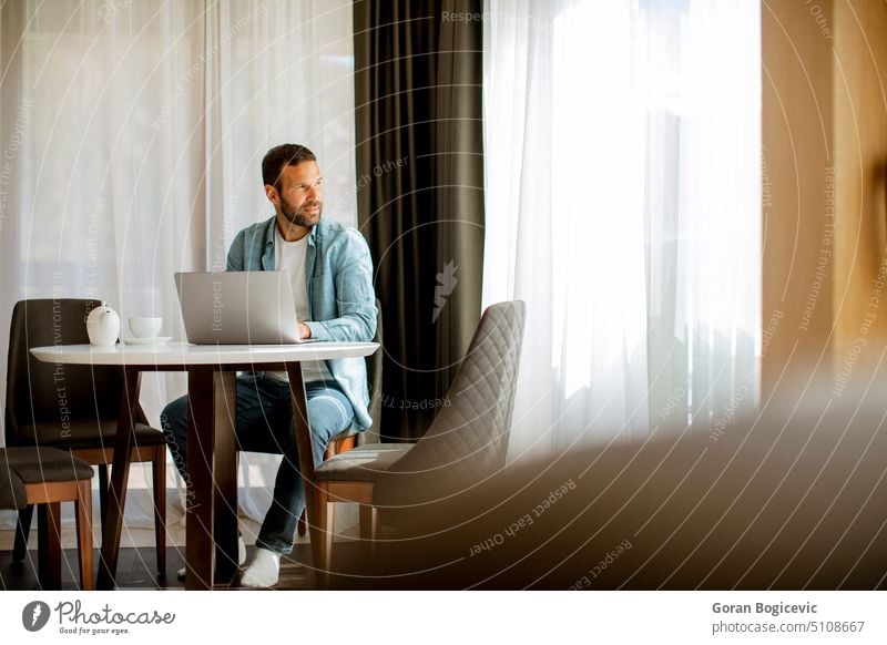 Junger Mann benutzt Laptop und trinkt Tee im Wohnzimmer Lifestyle Tasse Büro Computer modern Business Technik & Technologie trinken Unternehmer Job Internet