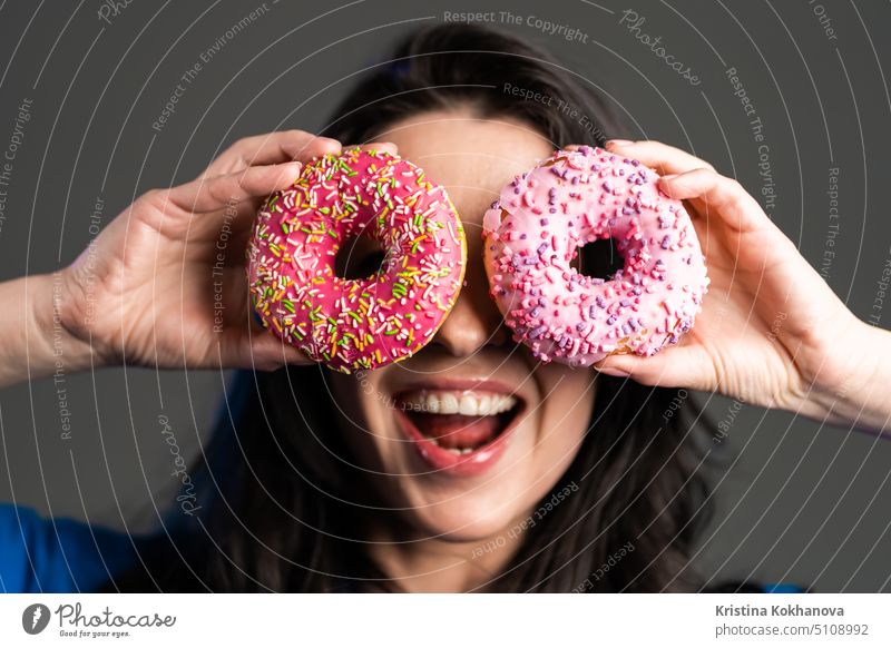 Porträt der fröhliche schöne Frau tanzen mit Süßigkeiten bunte Donuts isoliert auf grauem Hintergrund Studio. Konzept der Freude, Essen, Lebensstil. Person