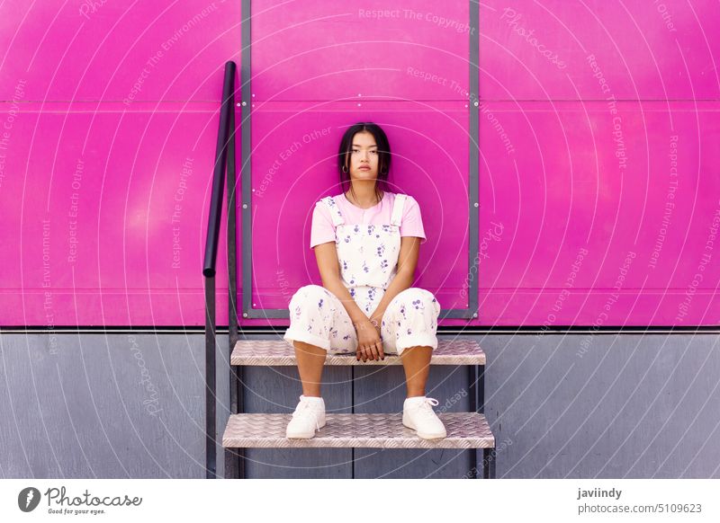 Asiatische Frau auf Stufen sitzend Gebäude Wand Schritt Stil urban Straße hell Vorschein Individualität jung ethnisch asiatisch Outfit Persönlichkeit lässig