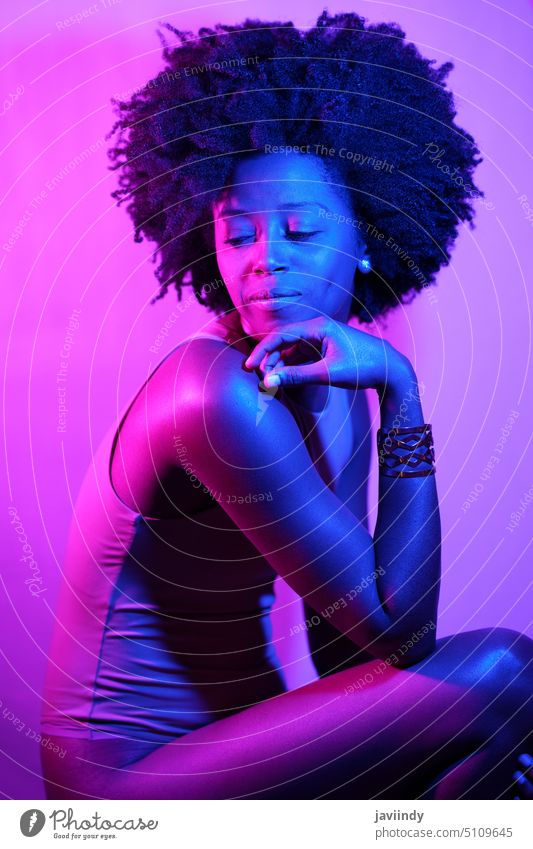 Afroamerikanisches Modell unter Neonbeleuchtung Frau Kinn berühren sinnlich neonfarbig violettes Licht schlank Vorschein Body leuchten schwarz Afroamerikaner