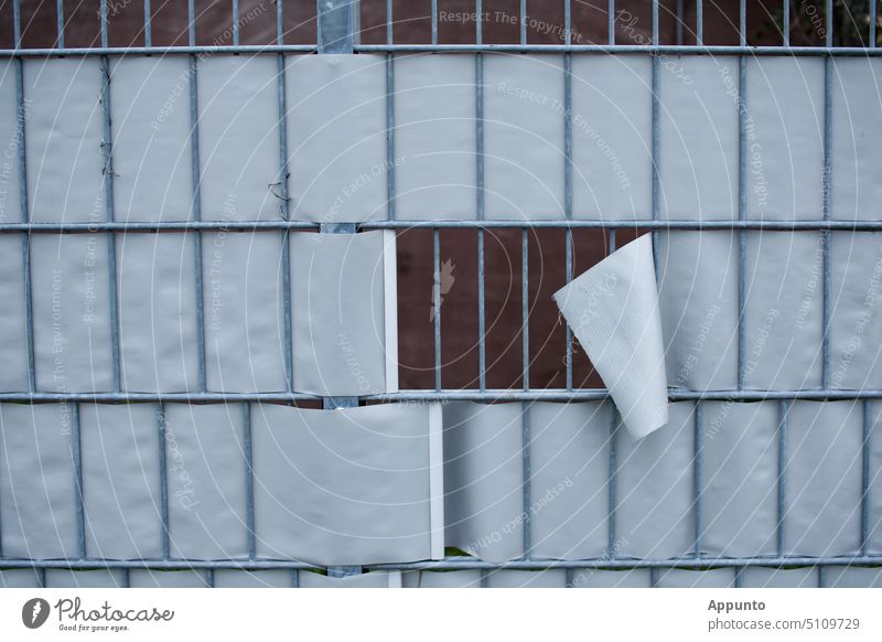 Schlupfloch in einem Drahtgitterzaun mit aufgerissener weißer Textilplane und Blick auf rotbraunen Hintergrund Zaun Plane Öffnung Freiheit Barriere Loch Boden