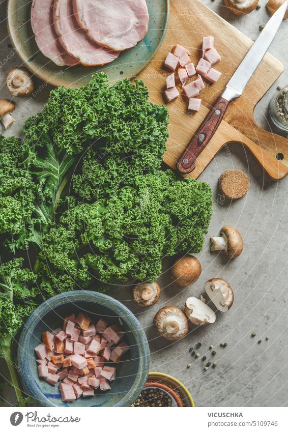Roh kale mit Schinken und Pilzen auf Küchentisch, Kochvorbereitung Draufsicht. grünkohl essen kochen