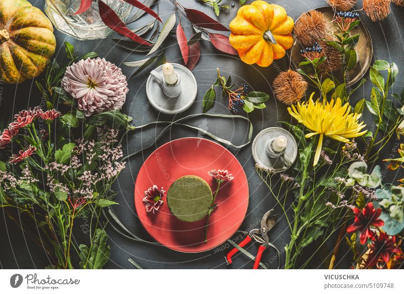 Verschiedene Blumen mit Kürbissen, Kerzen und Blumenschaum auf dunklem Tisch, Ansicht von oben. Herbstblumen Arrangement machen. verschiedene dunkel Draufsicht