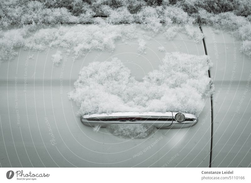 Weiße Autotür mit frisch gefallenem, herzförmigen Schnee auf dem Türgriff Winterlandschaft schneebedeckt winterlich Kälte Frost Wintertag Linien verschneit