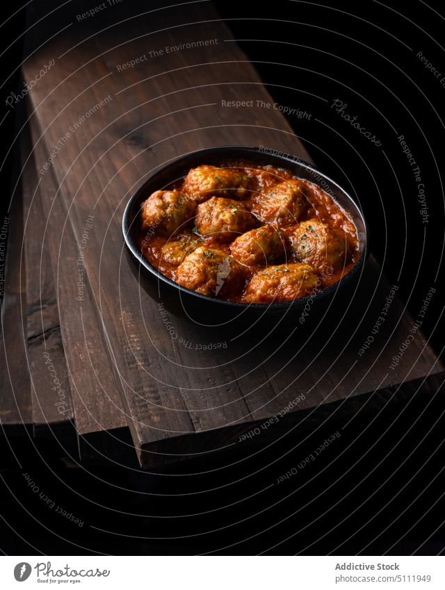 Leckere Fleischbällchen in Tomatensauce Lebensmittel Schalen & Schüsseln Fleischklößchen Saucen lecker Speise Holzplatte dunkel Küche geschmackvoll Kraut