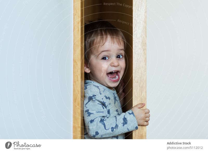 Lustiger Junge, der sich durch die Tür quetscht lustig drücken Wand schreien Kleiderschrank spielerisch niedlich spielen heimwärts Kind Pyjama Mund geöffnet
