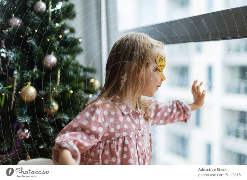 Mädchen schaut am Weihnachtstag aus dem Fenster Weihnachten heimwärts neugierig berühren Glas Weihnachtsbaum warten feiern Feiertag festlich Kind Dezember