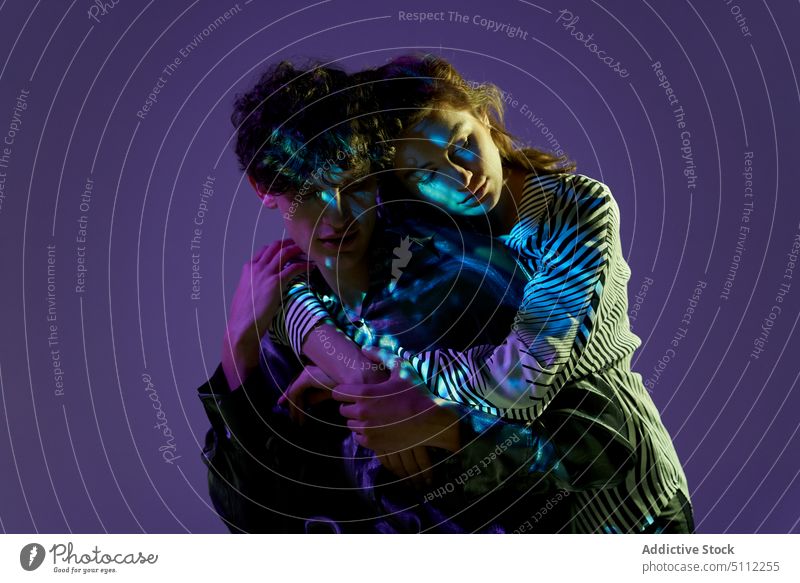 Sanftes Modellpaar, das sich im Neonlicht umarmt Paar neonfarbig Atelier Zeitgenosse Bekleidung dunkel romantisch Individualität Kleidungsstück Stil Liebe