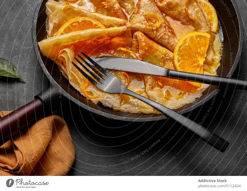 Hausgemachte Crêpes Suzette mit Orangenlikör und Orangenscheibe Pfanne serviert Beton Cointreau Gabel und Messer Europäer Zucker Textfreiraum Pfannkuchen heiß