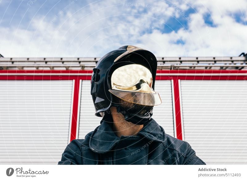 Selbstbewusster Feuerwehrmann in Uniform und Helm selbstbewusst Schutzhelm Garage Station Arbeit Notfall professionell Porträt männlich selbstsicher