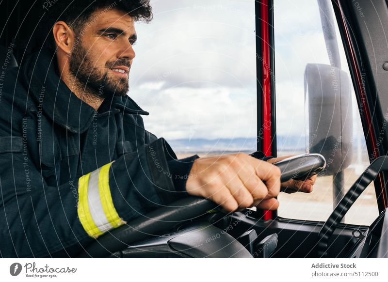 Hispanischer Feuerwehrmann fährt Feuerwehrauto Laufwerk Lächeln Arbeit Notfall freundlich Uniform behüten Porträt männlich Erwachsener hispanisch ethnisch