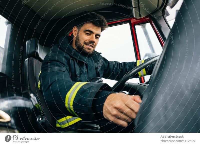 Feuerwehrmann fährt Feuerwehrauto bei Tag Laufwerk Lächeln Kontrolle Presse Schaltfläche Armaturenbrett Arbeit retten männlich Erwachsener hispanisch ethnisch