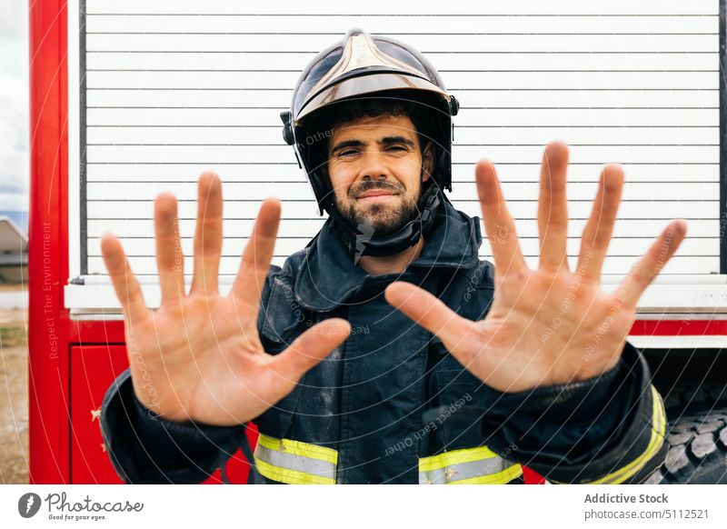 Männlicher Feuerwehrmann mit schmutzigen Händen zeigen Hand dreckig Uniform Lastwagen professionell Notfall Ruß Porträt männlich Erwachsener hispanisch ethnisch